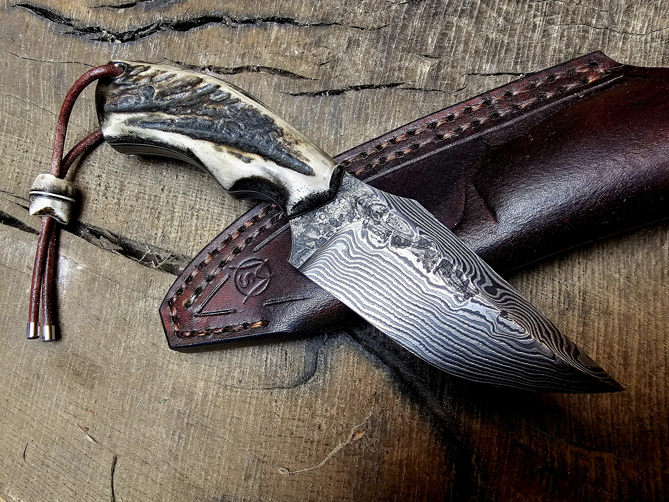Damast Jagdmesser mit Hirschhorngriff auf brauner handgenähter Lederscheide