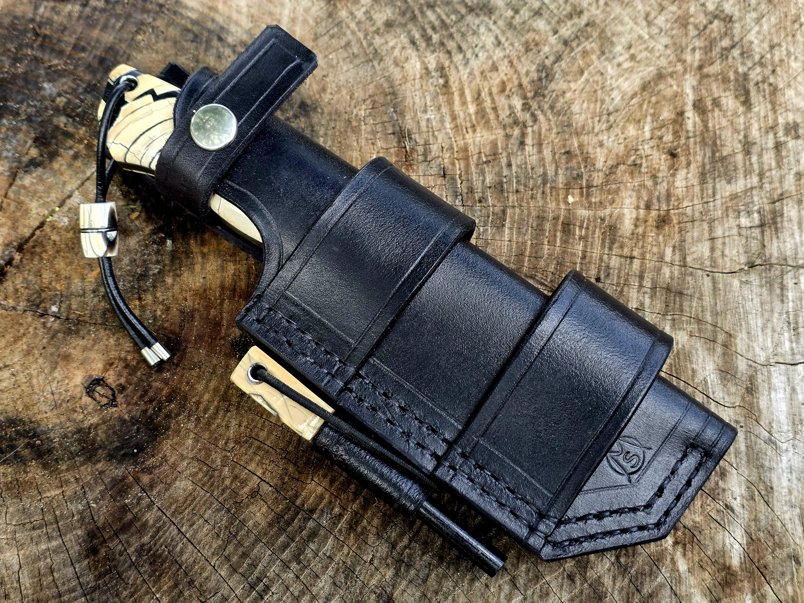 Bady K Spezial – Bushcraftmesser mit Lederscheide Handgefertigtes Bushcraftmesser Bady K mit Griff aus stabilisiertem Mammutelfenbein in schwarzer Lederscheide mit Feuerstahl und abnehmbarem Dangler.