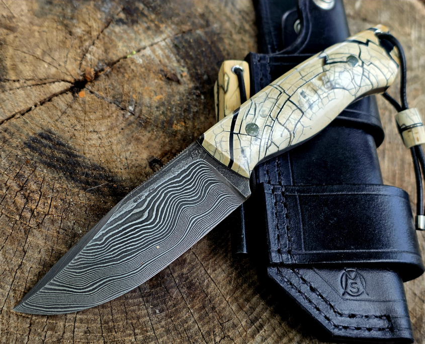 Bady K – Exklusives Bushcraftmesser aus Damast und Mammutelfenbein Handgefertigtes Bady K Bushcraftmesser mit Paschinger-Damastklinge, stabilisiertem Mammutelfenbein-Griff und schwarzer Bushcraft-Lederscheide.