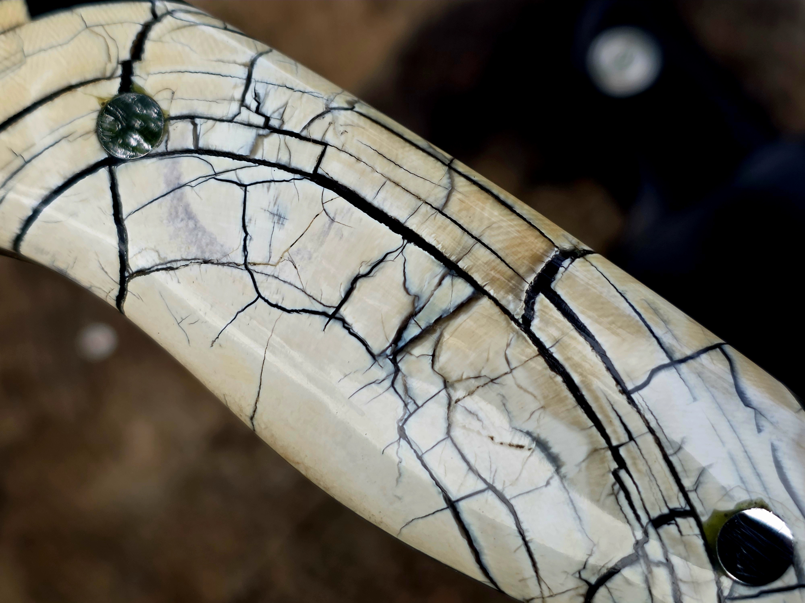 Bady K – Mammutelfenbein-Griff Detailaufnahme Nahaufnahme des Mammutelfenbein-Griffs am Bady K Bushcraftmesser mit schwarzer Maserung und sichtbarem Befestigungspin.