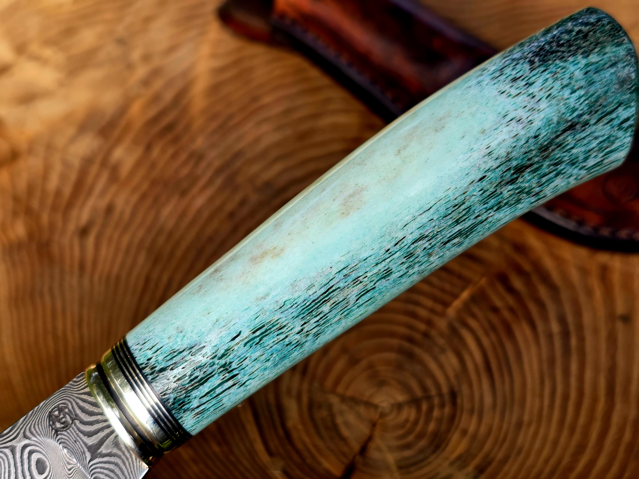Panah – Blau stabilisierter Hirschhorngriff Nahaufnahme des blau stabilisierten Hirschhorngriffs am Panah Jagdmesser mit Neusilberpassung und Balbachdamast.