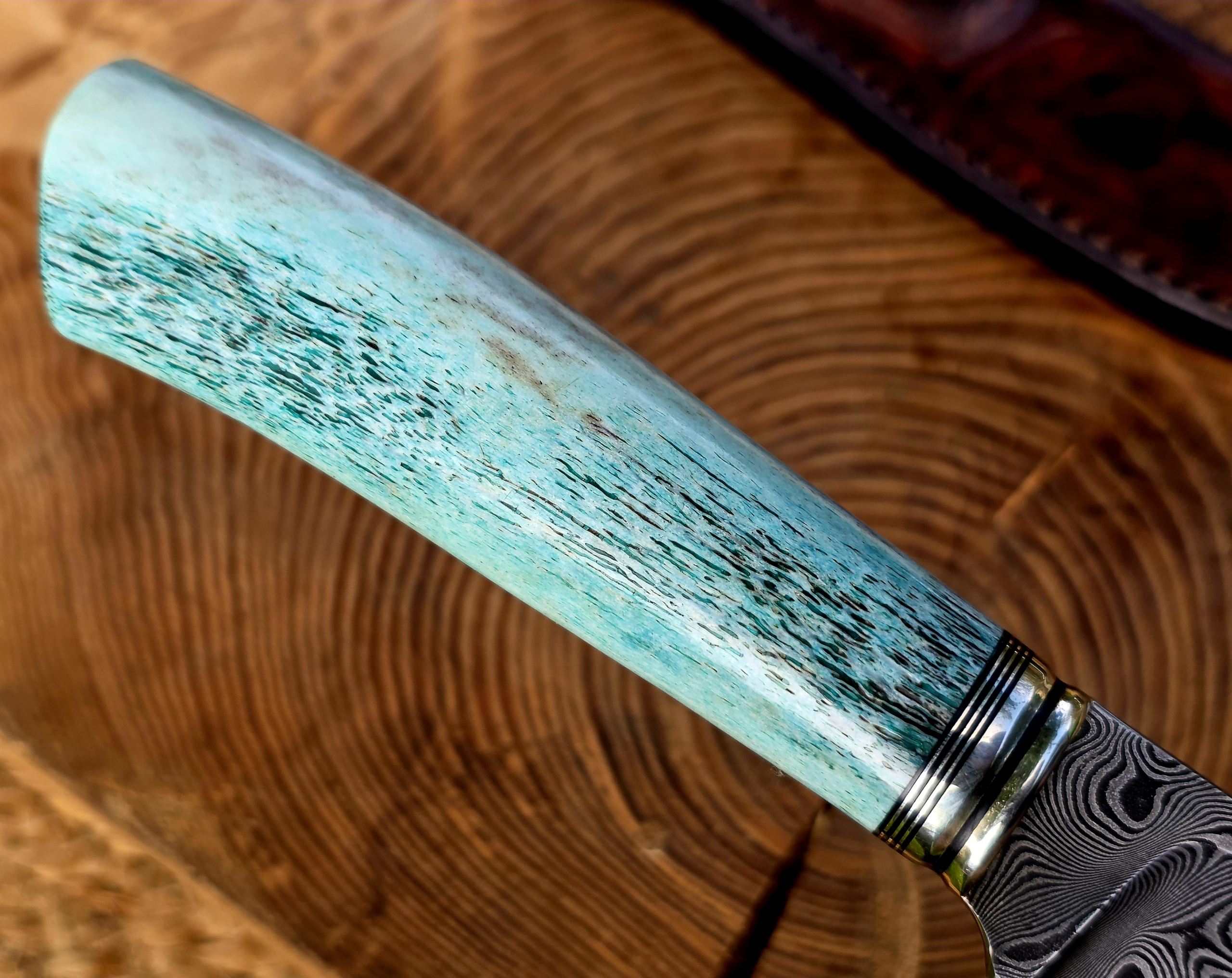 Panah – Hirschhorngriff in Blau Blau stabilisierter Hirschhorngriff des Panah Jagdmessers mit Neusilberringen und Balbachdamast-Klinge.