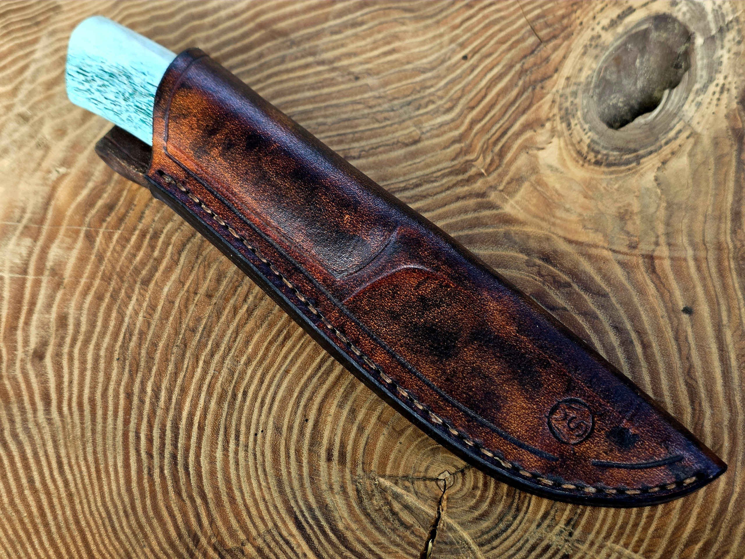 Panah – Jagdmesser mit Lederscheide Panah Jagdmesser mit blau stabilisiertem Hirschhorngriff in handgefertigter brauner Lederscheide.